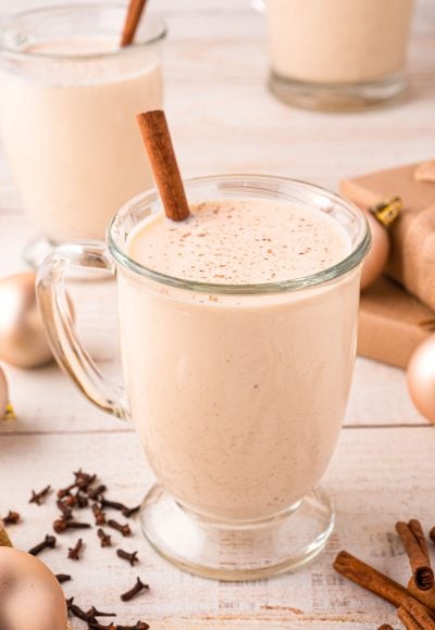 Close up photo of a mug of homemade eggnog on a light wooden counter.