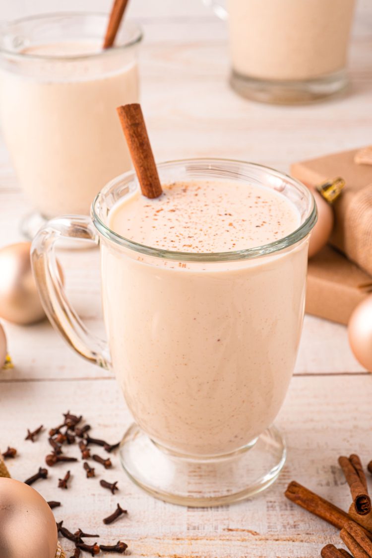 Close up photo of a mug of homemade eggnog on a light wooden counter.