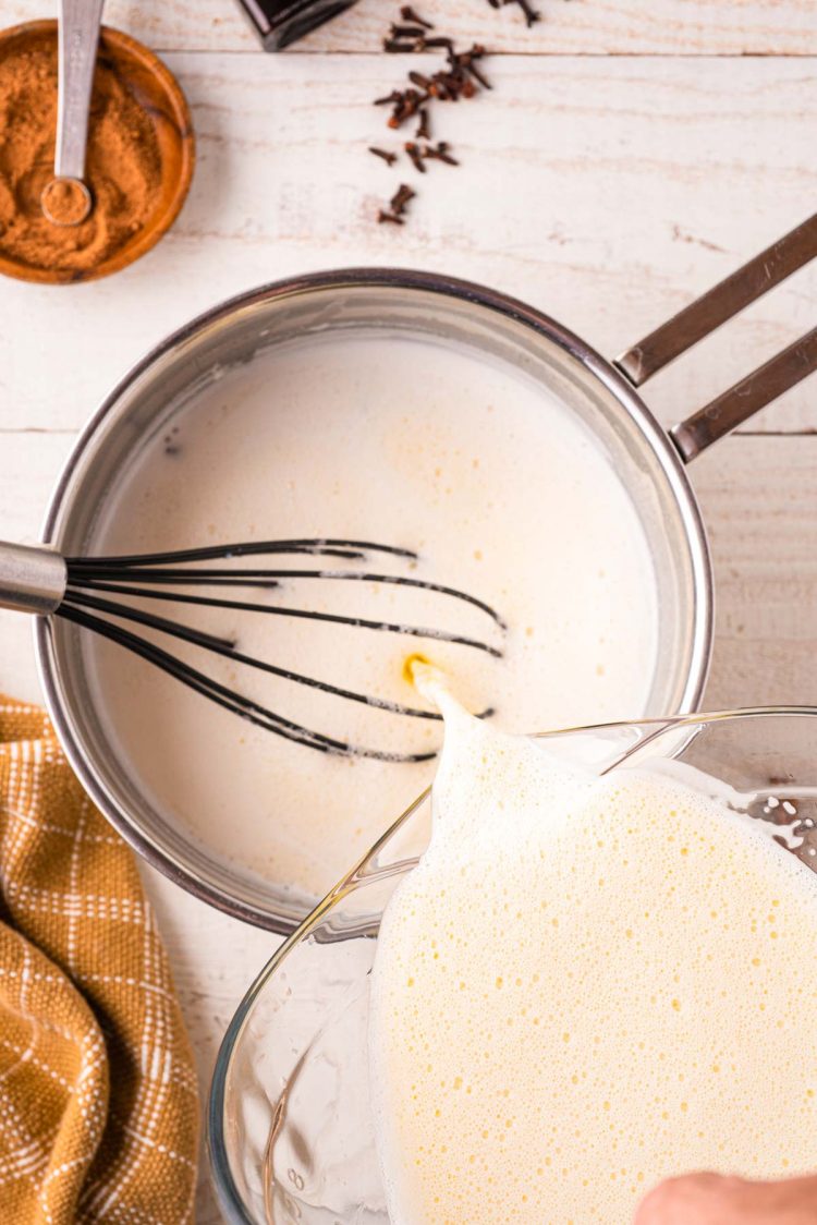 Tempered egg mixture being poured back into a pot.