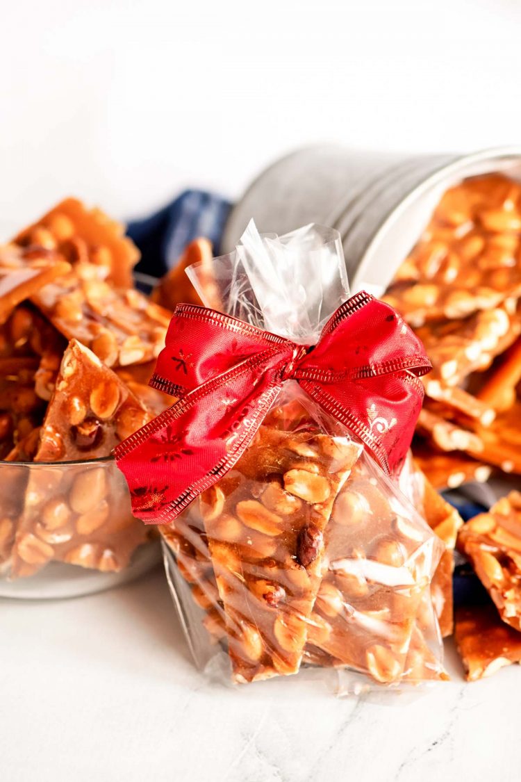 Peanut brittle wrapped up in a cello bag with red ribbon.