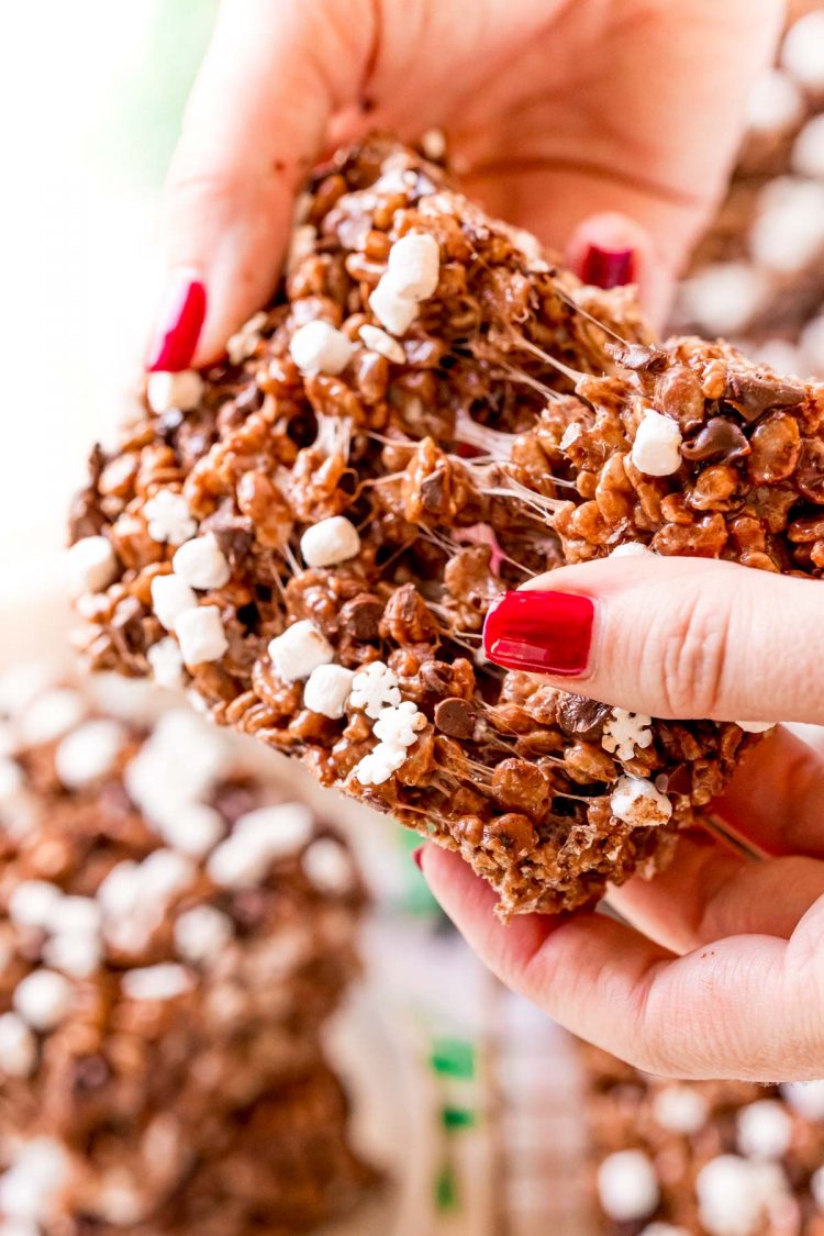 A woman's hand tearing apart a chocolate rice krispie treat.