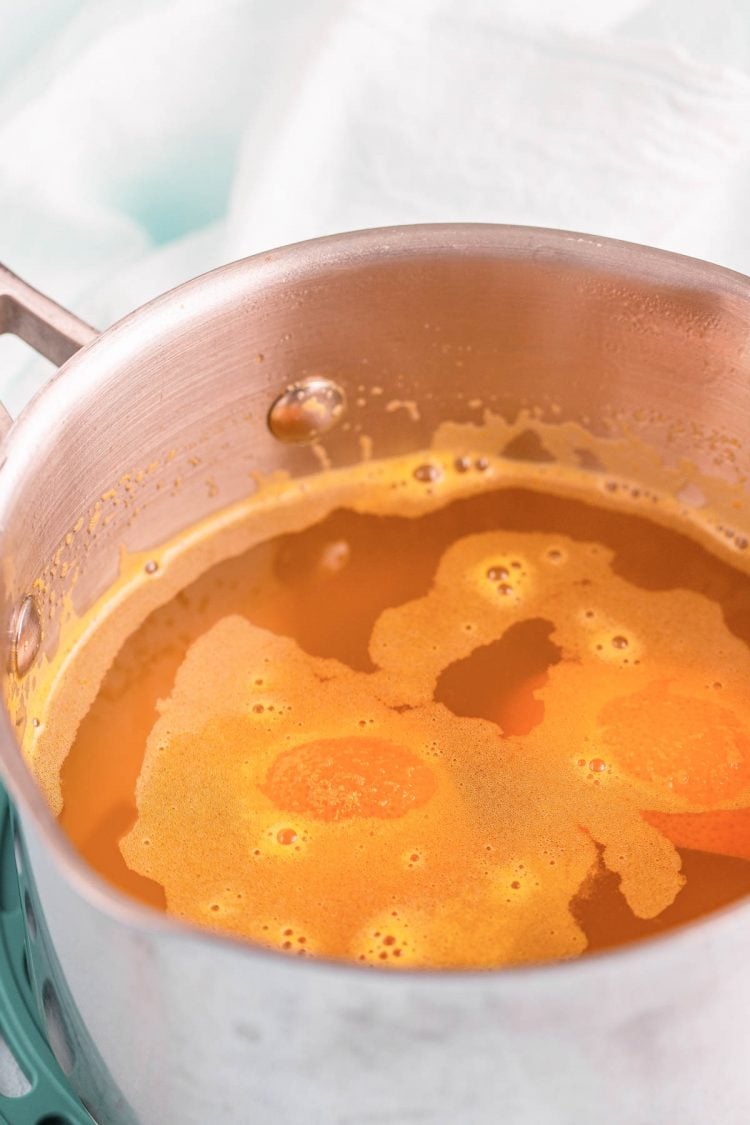 Orange simple syrup simmering in a small saucepan.