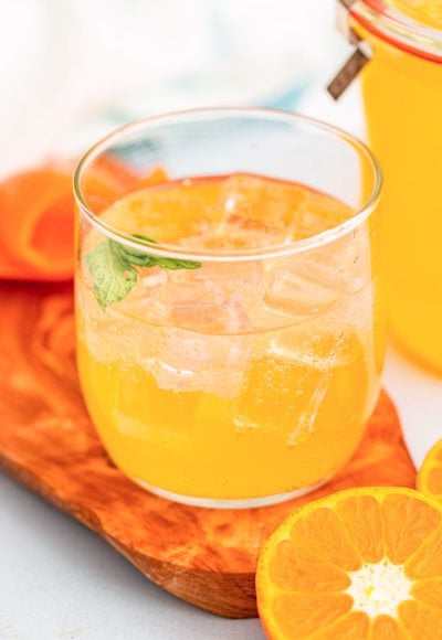 A glass with ice and orange simple syrup.