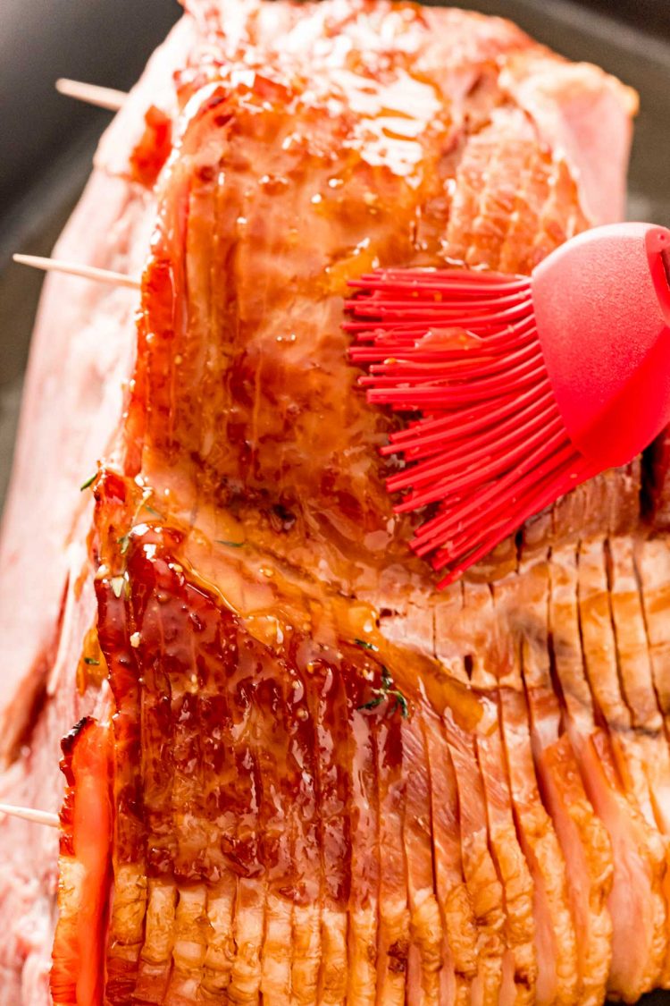 A spiral ham being brushed with glaze.