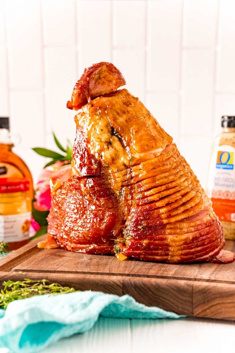 A spiral ham laying on the flat end on a wooden cutting board.