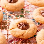 Close up photo of peanut butter blossoms on a copper wire rack.