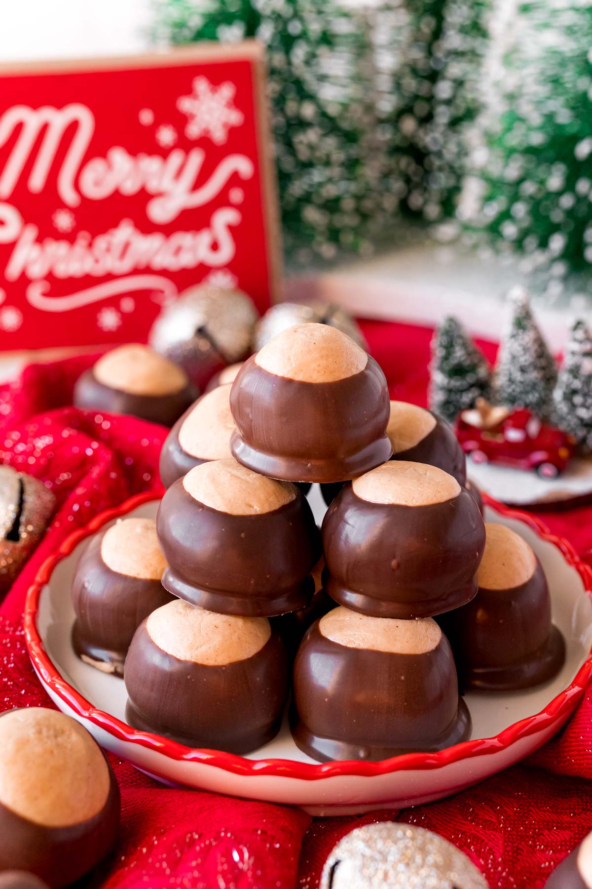 A stack of buckeye candies on a plate with holiday decorations around it.