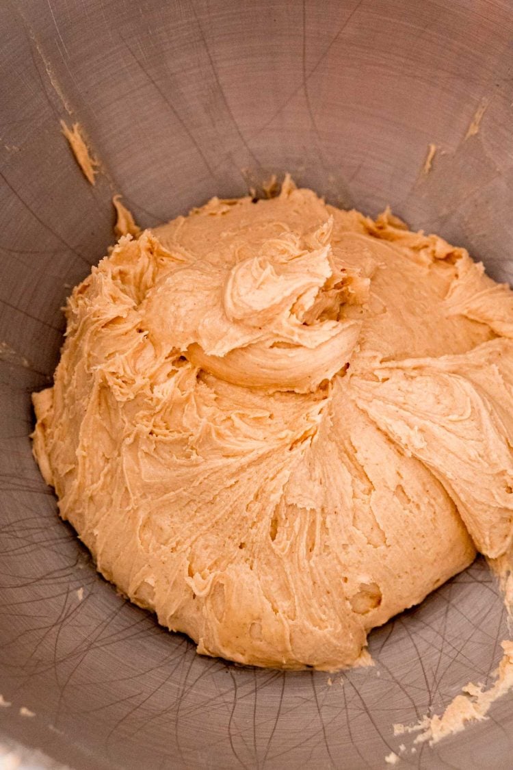 Peanut butter, butter, and powdered sugar mixed together in a metal mixing bowl.