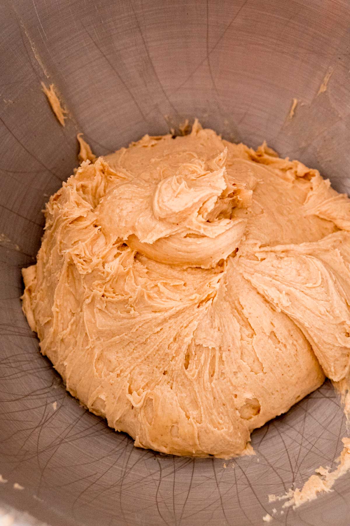 Peanut butter, butter, and powdered sugar mixed together in a metal mixing bowl.