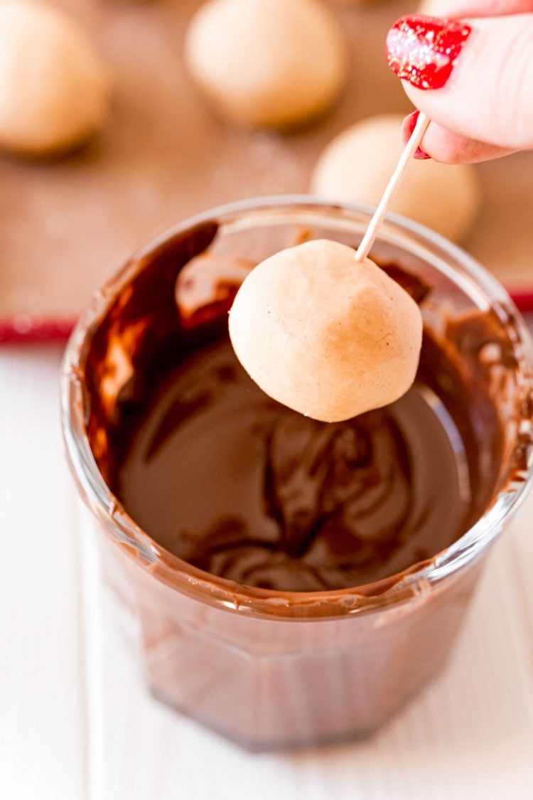 A peanut butter ball on a toothpick ready to be dipped in melted chocolate.