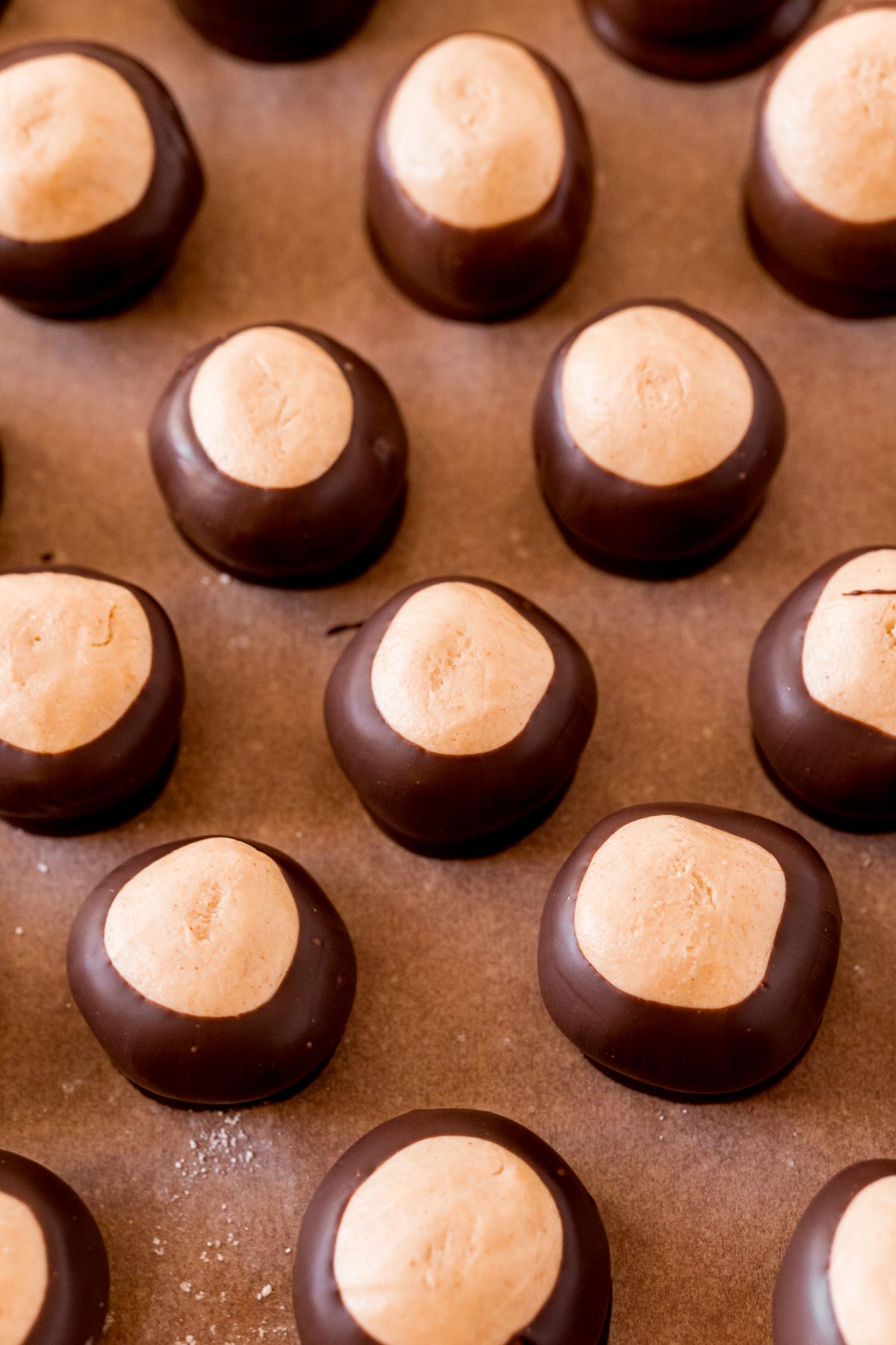 Peanut butter buckeyes on a sheet of parchment paper.