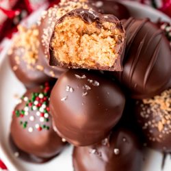 Close up photo of a stack of peanut butter balls on a white plate. The top one has a bite taken out of it.