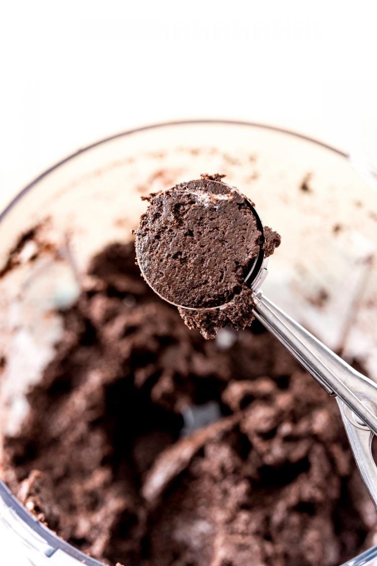A medium cookie scoop with oreo ball mixture in it.