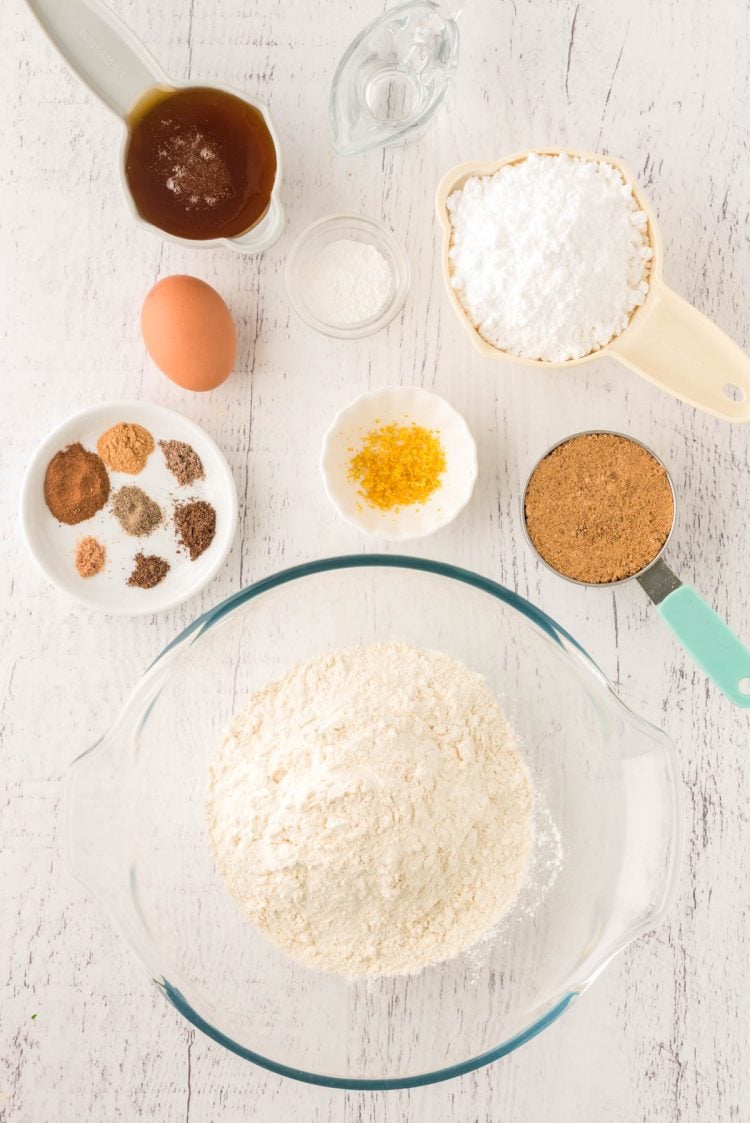 Overhead photo of the ingredients to make pfeffernusse cookies on a white wooden table.