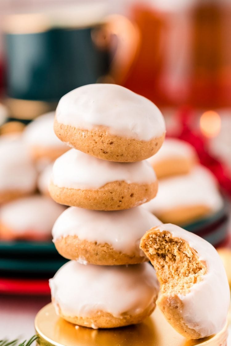 Stack of 4 pfeffernusse cookies with one cookie with a bite taken out of it leaning against the stack.