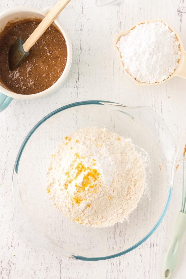 Overhead photo of a glass mixing bowl with flour and lemon zest in it.