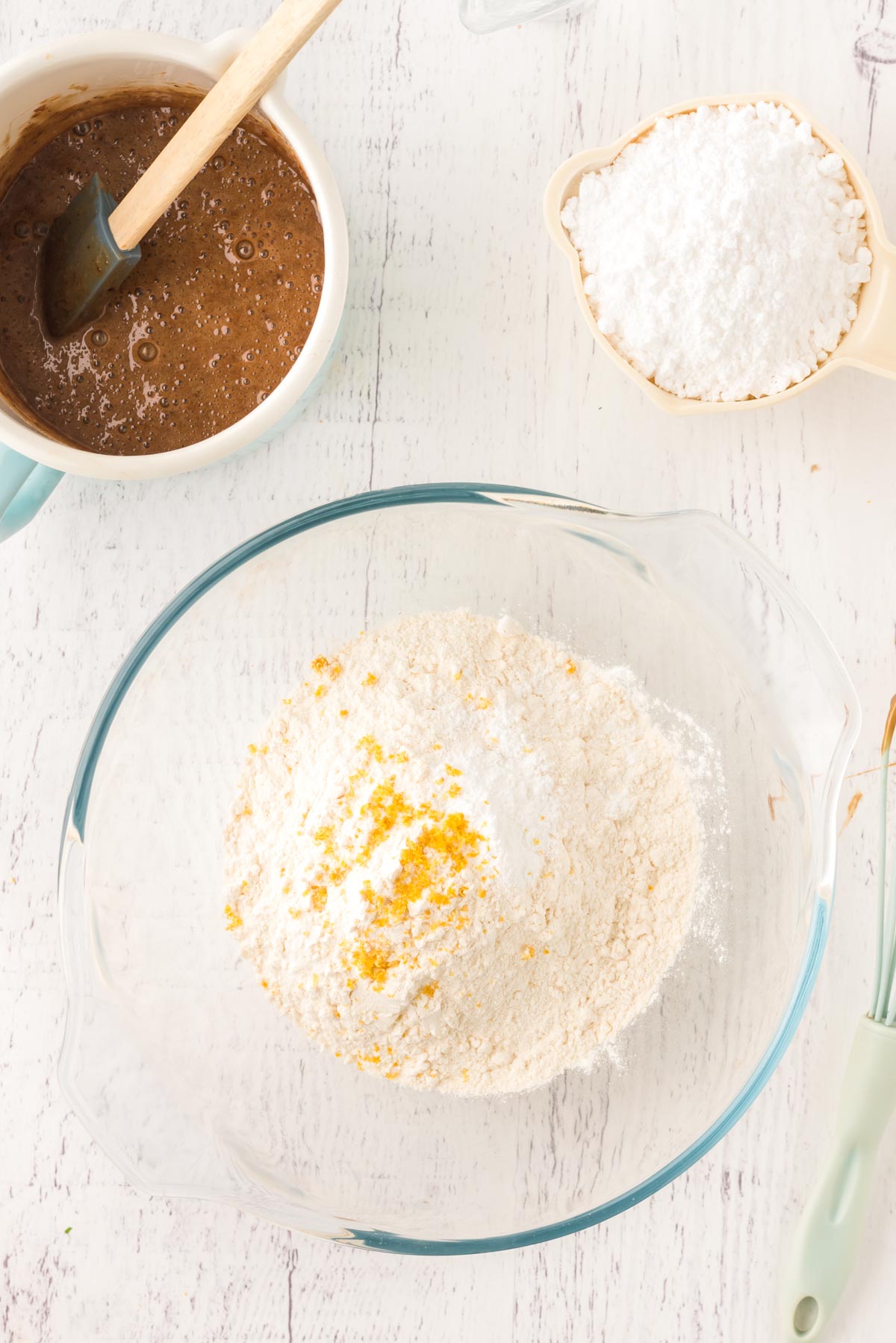 Overhead photo of a glass mixing bowl with flour and lemon zest in it.