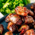 Close up photo of bacon wrapped dates piled on top of each other on a blue plate.
