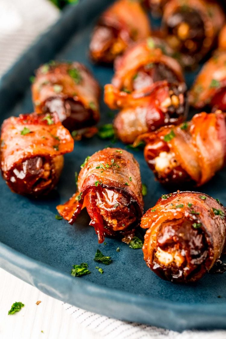 Close up photo of bacon wrapped dates on a blue serving platter.