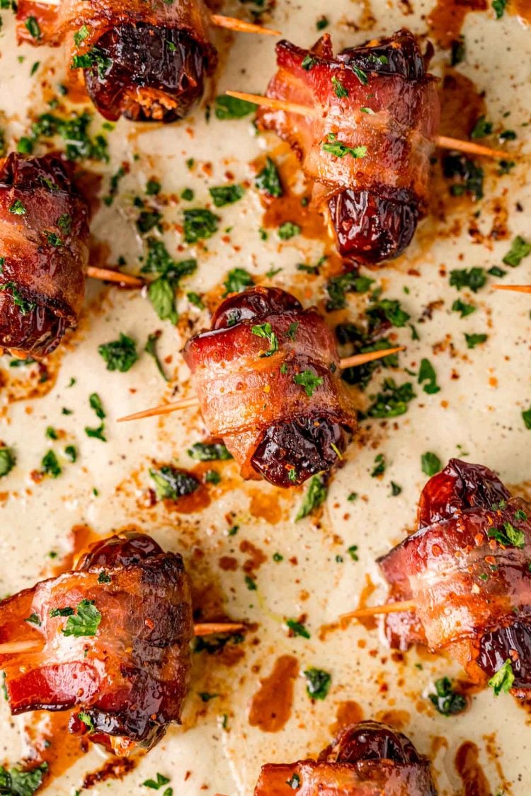 Overhead photo of bacon wrapped dates on a parchment lined baking sheet.