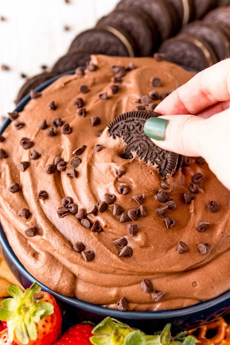 A woman's hand dipping an Oreo in brownie dip.