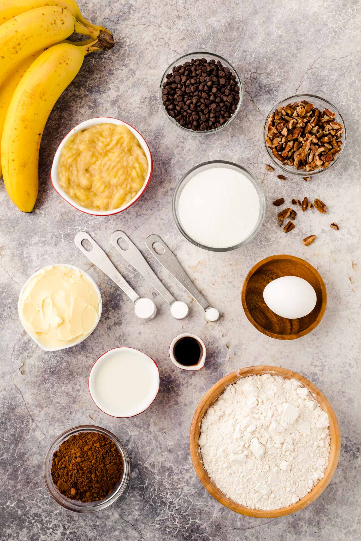 Overhead photo on ingredients to make chocolate banana muffins on a gray surface.