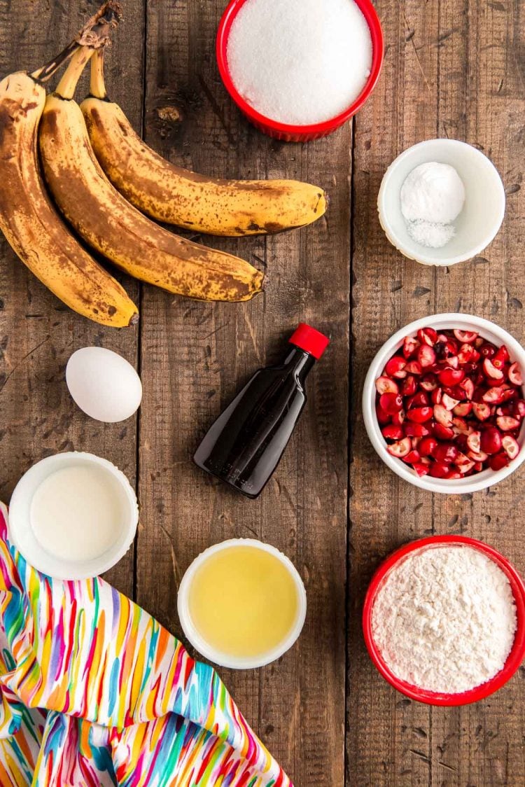 Ingredients to make cranberry banana bread on a wooden table.