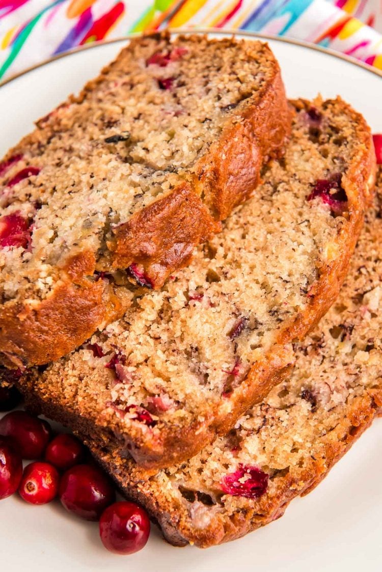 Close up photo of three slices of banana bread with cranberries in it laying on a white plate.