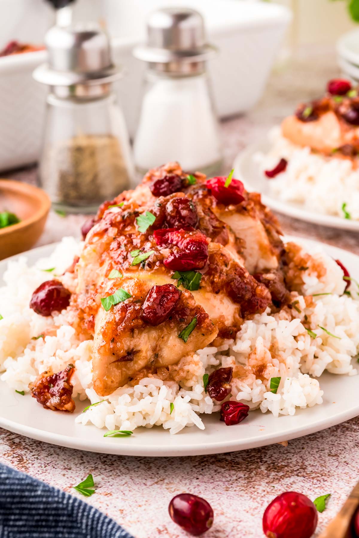 Close up photo of cranberry chicken on a bed of rice on a white plate.