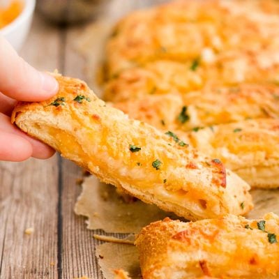 A woman's hand lifting a breadsticks away from a batch.