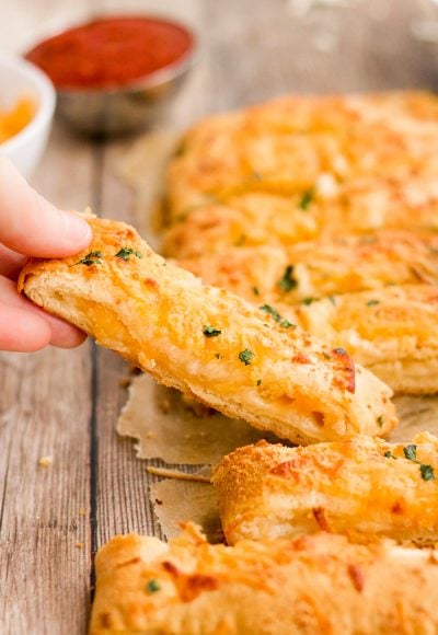 A woman's hand lifting a breadsticks away from a batch.