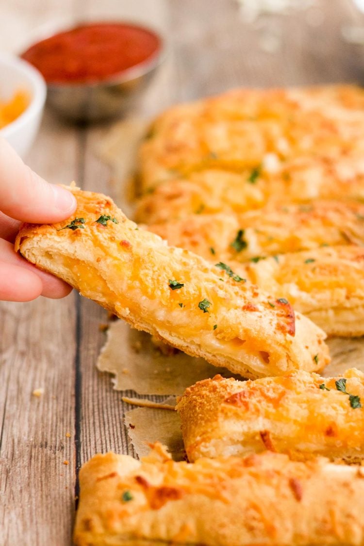 A woman's hand lifting a breadsticks away from a batch.