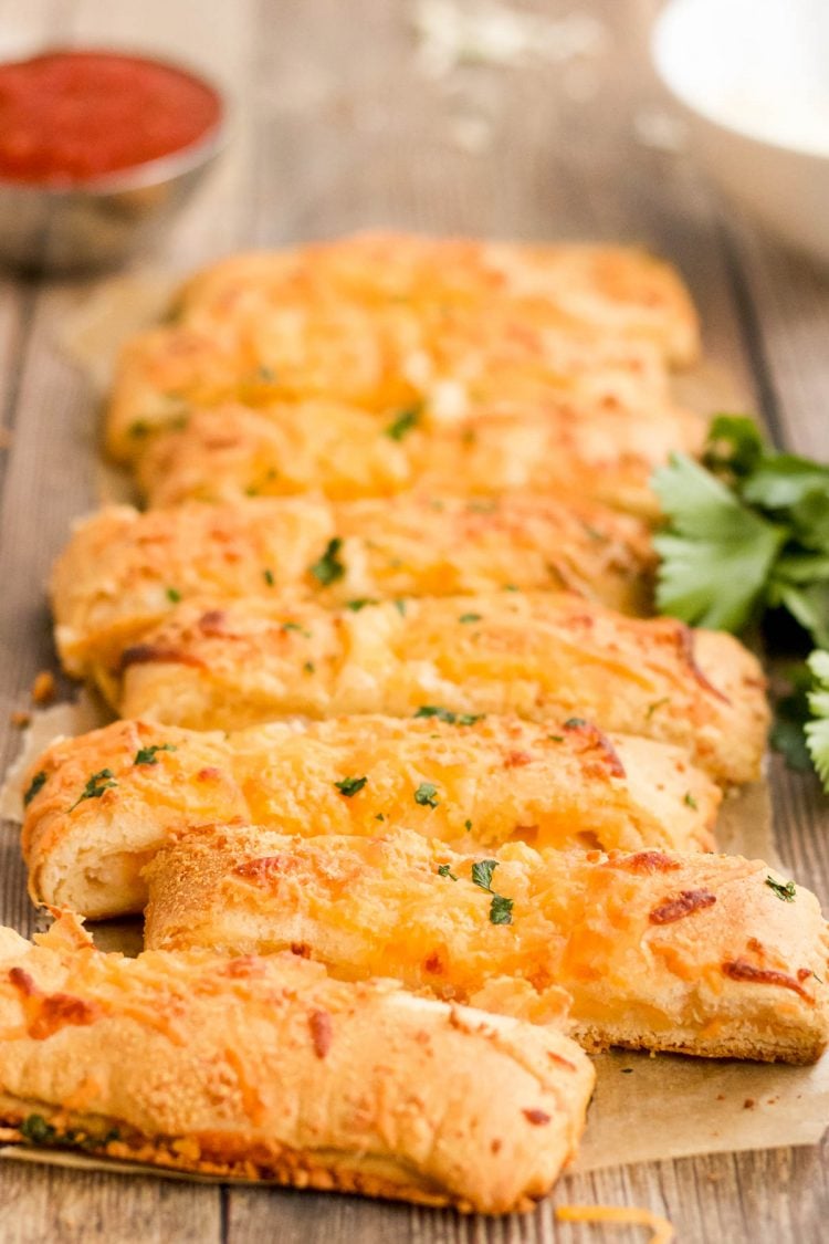 Breadsticks topped with cheese on a table ready to serve.