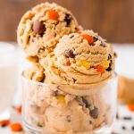 Close up photo of edible peanut butter cookie dough in a clear glass bowl.