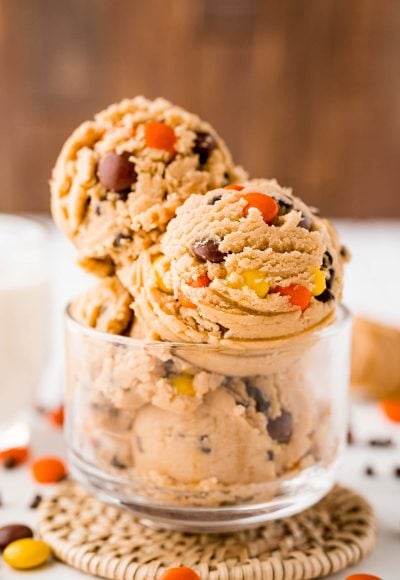 Close up photo of edible peanut butter cookie dough in a clear glass bowl.