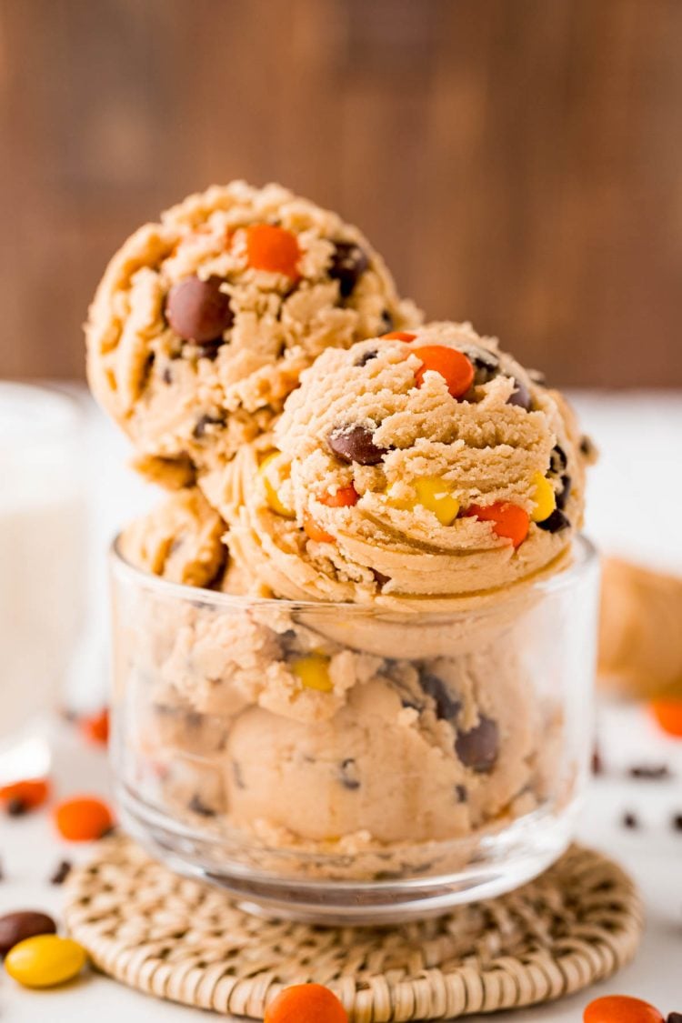 Close up photo of edible peanut butter cookie dough in a clear glass bowl.