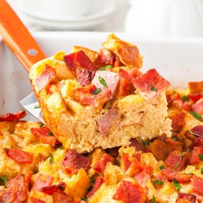 A slice of breakfast casserole being lifted out of a pan.