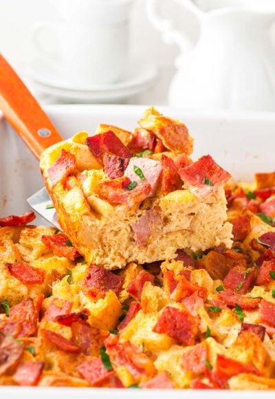 A slice of breakfast casserole being lifted out of a pan.