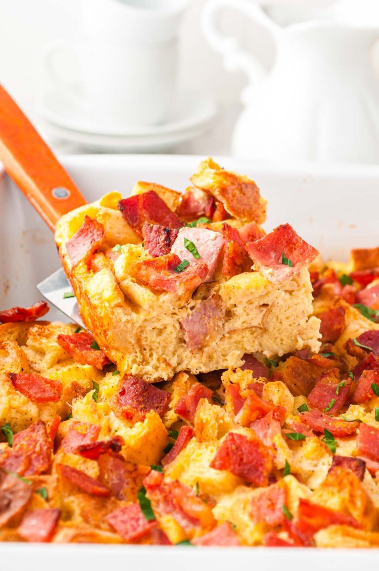 A slice of breakfast casserole being lifted out of a pan.