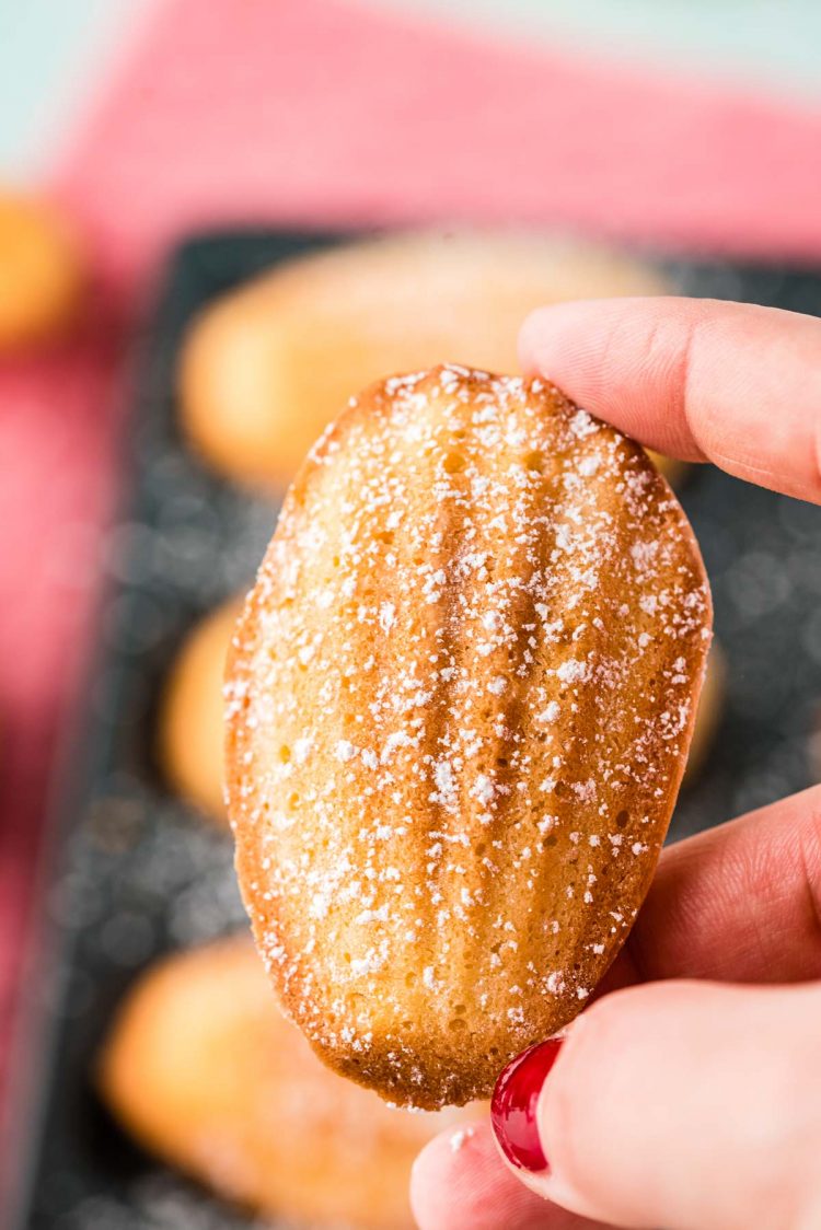 A woman's hand holding a madeleine.