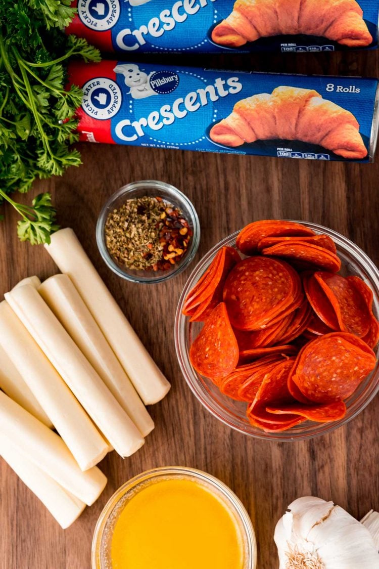 Ingredients to make pizza rolls on a wooden cutting board.