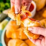 Close up photo of a pizza roll being pulled apart by a woman's hands.