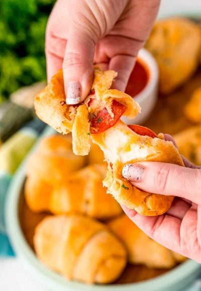 Close up photo of a pizza roll being pulled apart by a woman's hands.