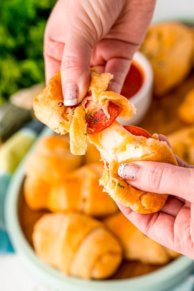 Close up photo of a pizza roll being pulled apart by a woman's hands.