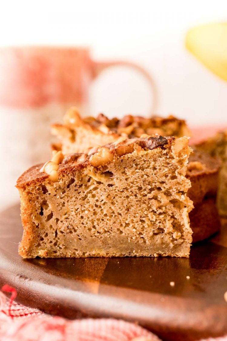 Close up photo of a slice of banana bread on a wooden cutting board.