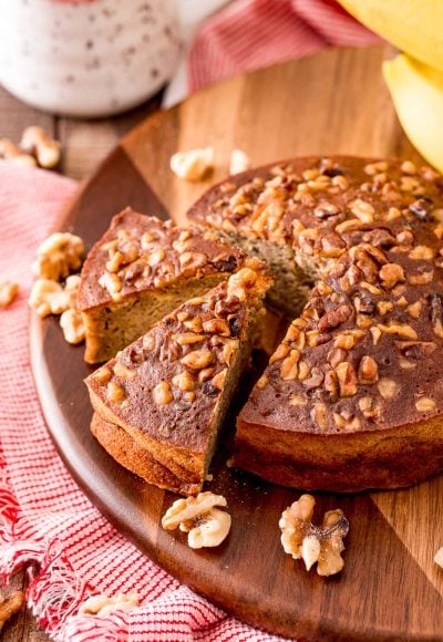 A round loaf of banana bread that's been cooked in the air fryer on a wooden cutting board.