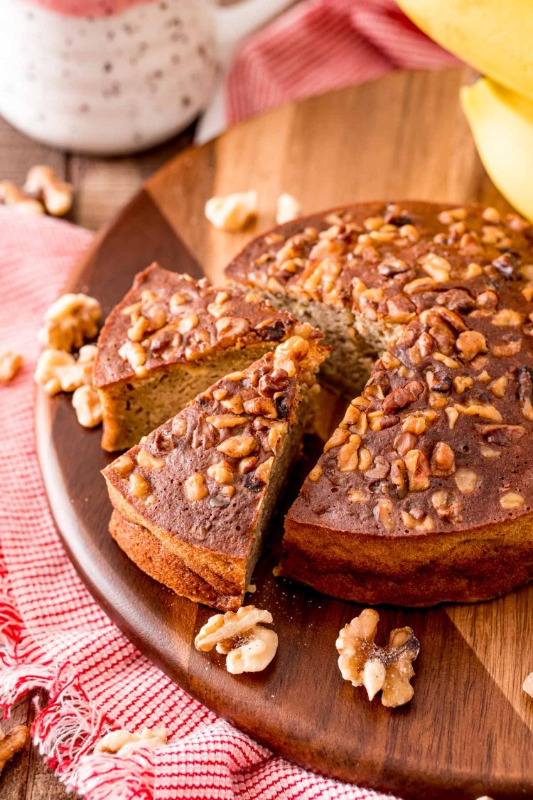 A round loaf of banana bread that's been cooked in the air fryer on a wooden cutting board.