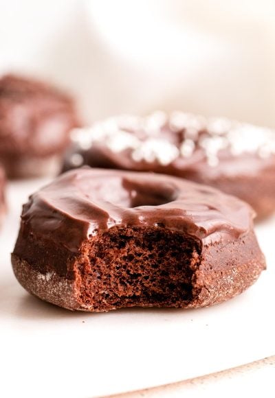 Close up photo of a chocolate donut with a bite taken out of it.
