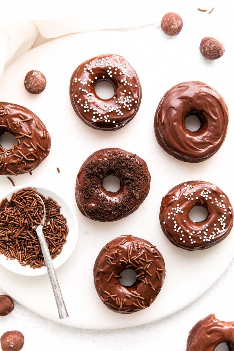 Overhead photo of chocolate donuts on a white serving plate.