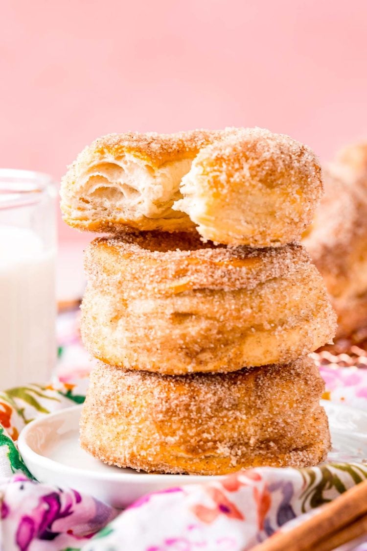 Three cinnamon sugar donuts stacked on top of each other with a bite taken out of the top one.
